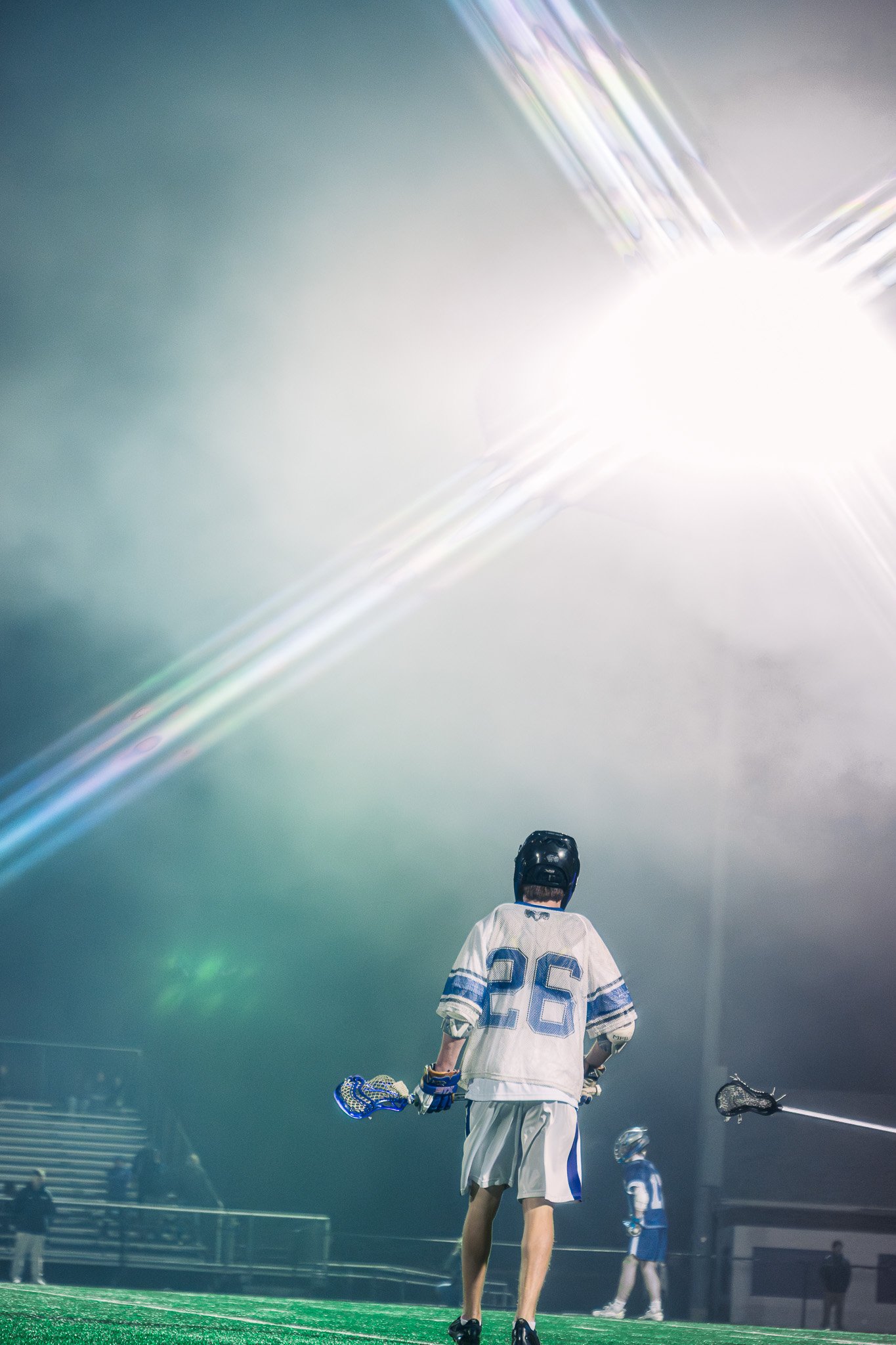 Lacrosse player under stadium lights with fog